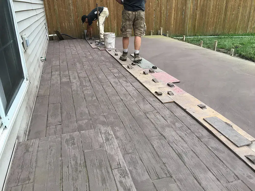 Northland Concrete Services workers stamping fresh concrete to create a high-quality stamped concrete patio with a decorative finish.